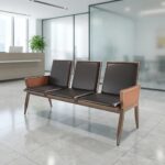 3-seater black waiting bench featuring three individual interconnected seats with smooth black faux leather padded backrests and seat cushions, integrated enclosed armrests with matching black upholstered panels, and a sturdy matte gunmetal gray metallic frame with tapered angular legs.