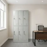 Light grey 6-door steel locker cabinet with recessed handles, individual key locks, and ventilation louvers next to an office desk.