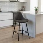 Dark gray faux leather barstool with a ribbed vertical-tufted backrest and tapered black metal legs with a built-in footrest.
