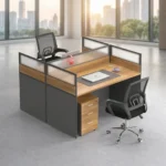 2 way office workstation arranged in a face-to-face configuration, featuring natural wood grain tabletops enclosed by charcoal gray privacy partition panels topped with frosted glass dividers, paired with a matching under-desk three-drawer mobile filing cabinet with lock.