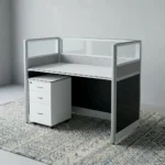 1-Way Office Workstation featuring a solid white desktop paired with a matching white under-desk three-drawer mobile filing cabinet with a key lock, enclosed by modern charcoal gray framed privacy partition panels decorated with a textured geometric pattern and topped with clear glass dividers.