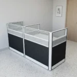 2 seater modular workstation featuring a side-by-side dual cubicle layout, enclosed by multi-paneled privacy screens with charcoal gray textured lower panels, light gray scribbled mid-panels, and slatted translucent frosted glass toppers set in a sleek black and silver aluminum frame.