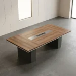 2.4m conference meeting table featuring a natural wood-grain tabletop with white edge trim, a central black media connectivity panel, and dual charcoal gray block pedestal legs.