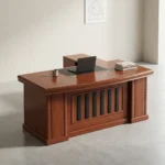 1.8m executive office desk featuring a rich, reddish-brown wood-grain finish, an integrated black writing pad inlay with dual grommet holes, a matching L-shaped side return cabinet, and a classic front modesty panel accented with vertical black inserts.