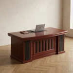 1.8m executive office desk featuring a rich, reddish-brown wood-grain finish, an integrated black writing pad inlay with dual grommet holes, a matching L-shaped side return cabinet, and a classic front modesty panel accented with vertical black inserts.