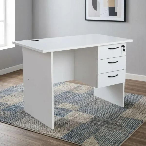 1.0m office study desk featuring a clean white finish, a circular black cable grommet on the tabletop, a matching modesty panel, and an integrated three-drawer pedestal with black curved handles and a lockable top drawer.