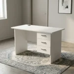 1.0m office study desk featuring a clean white finish, a circular black cable grommet on the tabletop, a matching modesty panel, and an integrated three-drawer pedestal with black curved handles and a lockable top drawer.