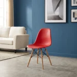 Red Eames plastic chair featuring a molded red plastic shell seat, tapered natural wooden legs, and black metal wire Eiffel-style cross-bracing.