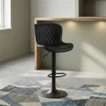 Black leather adjustable barstool featuring a curved bucket-style seat with diamond-quilted black leather upholstery, a matte black height-adjustable pedestal stand with a built-in oval footrest, and a matching circular trumpet base.