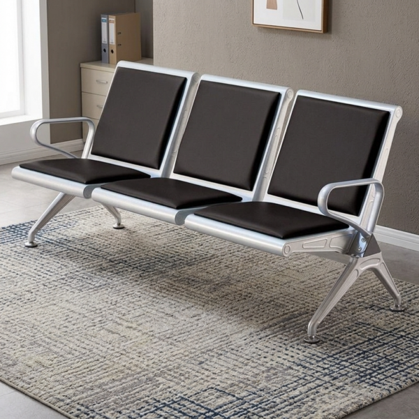 Heavy duty reception waiting bench featuring a robust three-seater silver metallic frame, padded black leather seat and backrest cushions for each section, integrated curved silver armrests at both ends, and angled support legs with adjustable leveling feet.