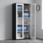 Full glass lockable file cabinet featuring a modern two-tone design with a black outer frame and white-trimmed double doors, large clear glass panels showcasing multi-tier internal shelving, a sleek integrated vertical handle, and a central key-lock mechanism.