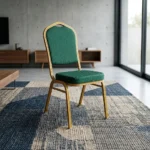 Stackable green banquet chair featuring a crown-top backrest and a thick square seat cushion, both upholstered in dark green fabric with a subtle gold fleck or dot pattern, supported by a sturdy gold-finished metallic frame with integrated stacking bumpers.