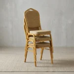 Stackable brown conference chair featuring a crown-top backrest with a cut-out handle and a thick square seat cushion, both upholstered in a textured light-brown or beige patterned fabric, shown in a vertical stack of three supported by a sturdy gold-finished metallic frame with integrated stacking bumpers.