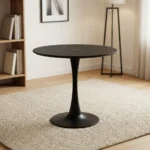 Modern black dining table featuring a sleek tulip-style design with a smooth matte-black circular tabletop, supported by a central tapered pedestal stem that flares out into a matching wide circular base.
