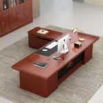 2.2m executive office desk featuring a classic rich cherry-red wood finish, an L-shaped layout with an attached side return cabinet, an embedded black writing pad on the main desktop, and a front modesty panel centered with a dark recessed section and a geometric accent.