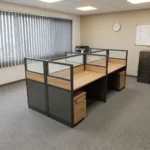 4-way modular workstation featuring four light oak-finish desks arranged in a 2x2 cluster, separated by semi-private partition screens with dark gray lower panels, light oak accent trim, and frosted glass upper sections, complete with individual under-desk three-drawer mobile pedestals and integrated desktop cable grommets.