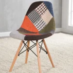 Modern patchwork Eames-style chair featuring a contoured shell seat upholstered in a multi-patterned fabric blend of houndstooth, plaid, and solid earthy tones, supported by natural wood dowel legs with black metal Eiffel-style wire bracing.