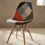 Modern patchwork Eames-style chair featuring a contoured shell seat upholstered in a multi-patterned fabric blend of houndstooth, plaid, and solid earthy tones, supported by natural wood dowel legs with black metal Eiffel-style wire bracing.
