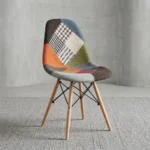 Modern patchwork Eames-style chair featuring a contoured shell seat upholstered in a multi-patterned fabric blend of houndstooth, plaid, and solid earthy tones, supported by natural wood dowel legs with black metal Eiffel-style wire bracing.