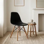 Black Eames-style dining chair featuring a molded matte black polypropylene shell seat, supported by natural wood dowel legs with black metal Eiffel-style wire bracing.