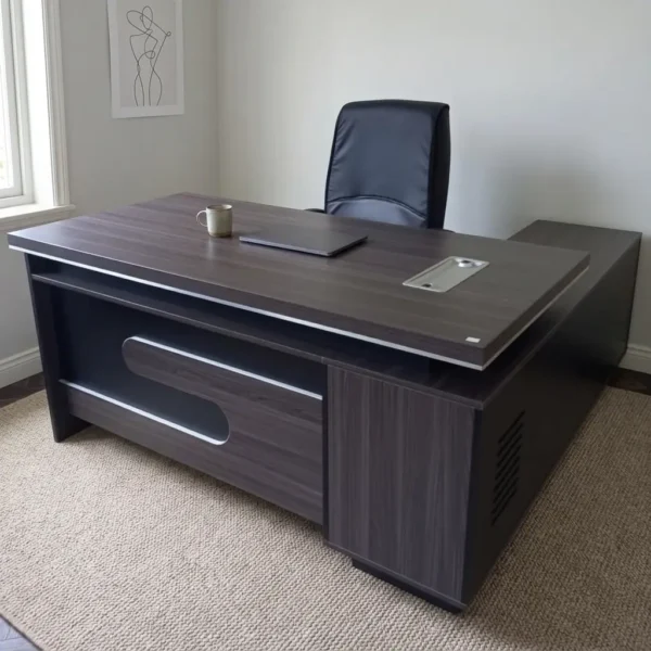 1600mm L-shaped executive table featuring a modern dark espresso wood-grain finish, integrated silver wire management grommets, an L-extension side credenza, and a recessed modesty panel with a stylized cut-out accent.