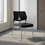 Stackable mesh visitor chair featuring a breathable black mesh backrest with a decorative geometric support accent, a armless design, a padded black fabric seat cushion, and a sleek chrome sled-base frame.