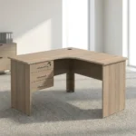 1.2m L-shaped office table featuring a light oak wood-grain laminate finish, a curved corner work surface, a built-in cable grommet, an integrated 3-drawer pedestal unit with lockable storage, sleek metal bar handles, and matching wooden panel legs.
