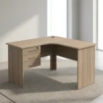 1.2m L-shaped office table featuring a light oak wood-grain laminate finish, a curved corner work surface, a built-in cable grommet, an integrated 3-drawer pedestal unit with lockable storage, sleek metal bar handles, and matching wooden panel legs.