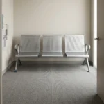 3-seater heavy-duty bench featuring perforated silver steel contoured seats and backrests, curved side armrests, and a durable steel beam support frame with adjustable blue-accented leveling feet.