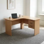 1.4m L-shaped office desk featuring a light oak wood-grain laminate finish, a curved corner desktop with an integrated cable grommet, wooden modesty panels, and an attached right-hand 3-drawer storage pedestal with dark curved handles and a key lock.