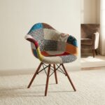 Eames-style patchwork armchair featuring a molded shell seat upholstered in vibrant multi-patterned fabric patchwork with integrated curved armrests, supported by dark wood legs and black metal Eiffel wire bracing.