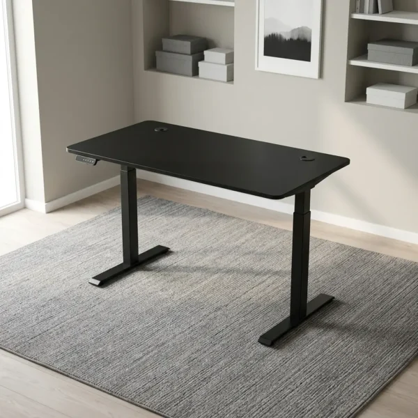 Height adjustable electric table featuring a sleek matte black desktop with dual cable management grommets, an under-desk digital control keypad, and heavy-duty black motorized telescoping legs supported by T-style flat feet.