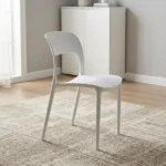 White plastic stackable chair featuring a minimalist molded matte white polypropylene single-piece construction, curved backrest with a lower rectangular cutout, contoured seat, and integrated tapered legs.