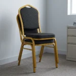 Black stackable conference chair featuring black fabric upholstery patterned with gold polka dots, a padded crown-back backrest and seat, and a durable gold-finished metal frame.