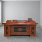 Executive 1800mm office table featuring a classic polished reddish-brown cherry wood finish, a gently curved front desktop with an embedded dark writing pad and cable grommets, decorative modesty paneling with dark inlay accents, and side pedestal bases.