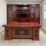 Executive 1800mm office table featuring a classic polished reddish-brown cherry wood finish, a gently curved front desktop with an embedded dark writing pad and cable grommets, decorative modesty paneling with dark inlay accents, and side pedestal bases.