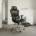 Recliner orthopedic chair with footrest featuring a breathable full-black mesh construction, an adjustable mesh headrest, a multi-segmented high backrest with specialized lower lumbar support, 3D adjustable armrests, a retractable mesh footrest, and a polished metallic five-star base on smooth-rolling casters.