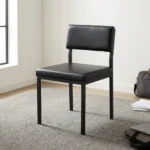 Black stackable catalina chair featuring a minimalist armless steel frame with a black powder-coated finish, a padded black faux leather low-profile backrest, a thick cushioned seat, and straight square legs.