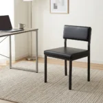 Black stackable catalina chair featuring a minimalist armless steel frame with a black powder-coated finish, a padded black faux leather low-profile backrest, a thick cushioned seat, and straight square legs.