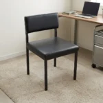 Black stackable catalina chair featuring a minimalist armless steel frame with a black powder-coated finish, a padded black faux leather low-profile backrest, a thick cushioned seat, and straight square legs.