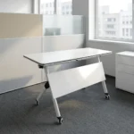 120cm foldable training table featuring a rectangular white laminate tabletop with a black edge band, integrated onto a white metal nesting frame with a matching solid white modesty panel, supported by angled T-legs equipped with dual-wheel locking casters.