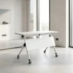 120cm foldable training table featuring a rectangular white laminate tabletop with a black edge band, integrated onto a white metal nesting frame with a matching solid white modesty panel, supported by angled T-legs equipped with dual-wheel locking casters.