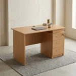 1.2m wooden office table featuring a light oak wood finish, a rectangular desktop with a circular wire management grommet, a half-height modesty panel, and an integrated side pedestal with three lockable drawers with metal bar handles.