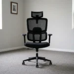 High-back orthopedic office seat featuring an all-black ergonomic design with a split mesh backrest, an adjustable mesh headrest, integrated dynamic lumbar support, a padded fabric seat cushion, height-adjustable T-armrests, pneumatic height adjustment lever, and a durable black five-star base on smooth-rolling casters.
