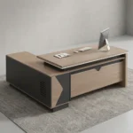 1.8m managerial executive office desk featuring a modern L-shaped design in natural wood grain and charcoal grey finishes, a floating-style primary desktop with a raised under-frame, an integrated low-profile side return cabinet with ventilation slats and geometric accent paneling, and a matching front modesty panel with a decorative top cutout.