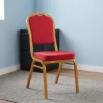 Stackable red conference chair featuring a crown-back gold-finished metal frame, padded seat and backrest upholstered in red patterned fabric with gold dot detailing, and four fixed legs with protective floor glides.