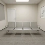 Heavy duty 4-seater waiting bench featuring a durable metallic silver-grey steel construction, four individual perforated metal seats and backrests, curved side armrests, a heavy-duty central support beam, and angled steel legs.