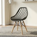Black plastic Eames-style chair featuring a molded seat with an open diamond-lattice backrest, a solid black seat pad, and natural wooden dowel legs with black metal wire Eiffel bracing.
