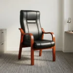 High-back executive visitors chair featuring plush black leatherette upholstery with stitched paneling, ergonomic lumbar and back support, padded seat cushion, and a sturdy solid wood frame with warm mahogany-finished curved armrests and four fixed legs.