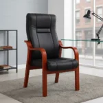 High-back executive visitors chair featuring plush black leatherette upholstery with stitched paneling, ergonomic lumbar and back support, padded seat cushion, and a sturdy solid wood frame with warm mahogany-finished curved armrests and four fixed legs.